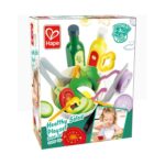 Дървен комплект Зеленчуци, Hape: кутия „Healthy Salad Playset“ с бяла купа маруля, домат и яйце между зелена и жълта бутилка дресинг, нож и лилав лук и с хапващо момиченце в ъгъла.