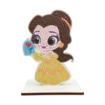 Диамантен гоблен Бел, Craft Buddy: фигурка с голяма глава от кристалчета в кестеняво и жълто, която държи роза и стои на светла дървена поставка.