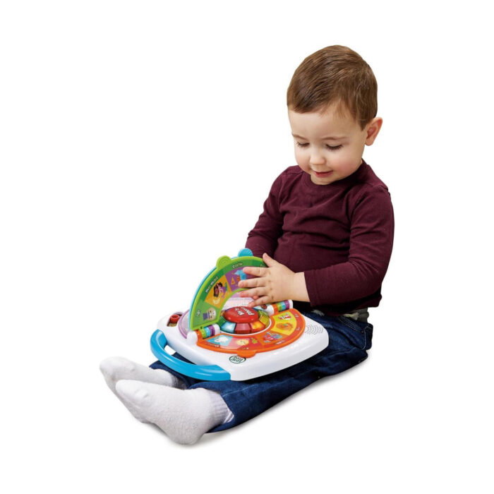 leap-frog-fonetichna-igra-zavarti-i-nauchi-vtech-1500 Leap Frog фонетична игра Завърти и научи, VTech: малко момче в бордо блуза седи и обръща зелените страници на бяло-оранжева играчка с червен бутон в средата и синя дръжка.