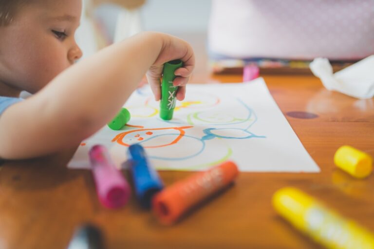 Дете на 3 до 4 години рисува с цветни пастели за въображение и творчество