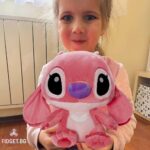 Момиче държи Розов Стич. Розова плюшена играчка с уши надолу.