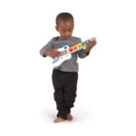 Момченце стои и свири на бялата китара Hape Baby Einstein