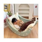 Момиченце, прегърнало плюшено мече, почива в зеления модул Feelkids, застлан с възглавница