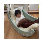 Момиченце лежи на възглавници в зеления модул Feelkids, обърнат като люлееща се лодка