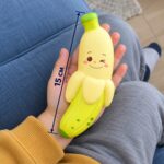Полуобелен скуиши банан с намигащо лице в детска длан, с линия за дължина 15 см.
