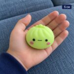 Зелен скуиши дъмплинг с личице в отворена детска длан, с надпис 5 см.