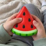 Скуиши диня, 9 см:: детски ръце натискат с палци червената среда на скуиши динята.