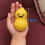 Жълтият скуиши фъстък с усмивка в отворена детска длан, с линия за височина 9,5 см.