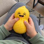 Детски ръце стискат жълтия скуиши фъстък в скута.