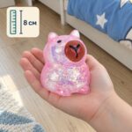 Розова скуиши капибара с брокат в детска длан, с означение за височина 8 см.