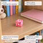 Розово скуиши кубче на дървен рафт до книги, с надписи за компактен размер 5 см и различни шарки; получавате 1 брой с модел изненада.