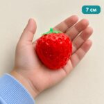 Малката червена скуиши ягода в отворена детска длан, с надпис 7 см.