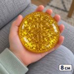 Златната скуиши монета в отворена детска длан, с надпис 8 см.