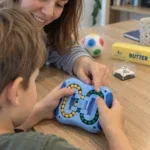 Детски палци плъзгат топчетата на IQ Ball, а мама сочи три еднакви цвята